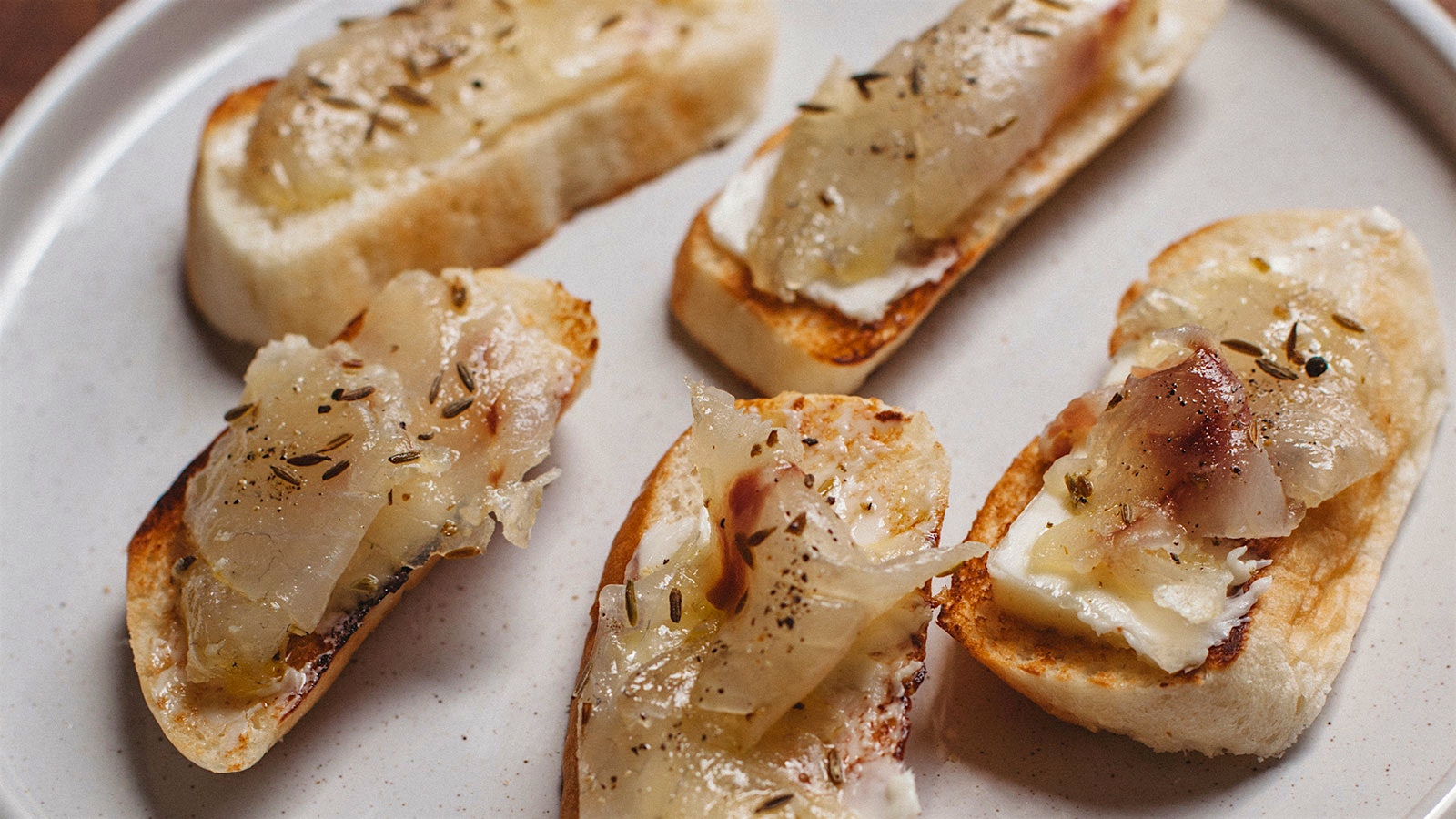 Branzino al Cumino on baguette slices.